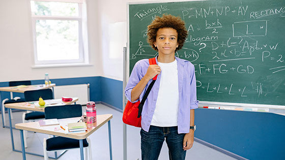 Student studying online for a business degree, using a laptop with books and notes at home.